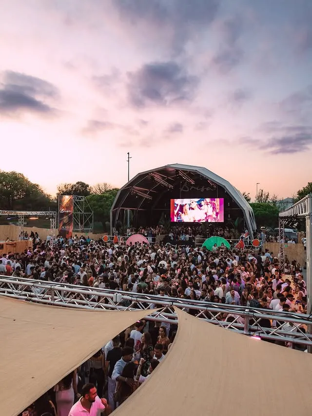 Escenario al anochecer con cielo rosa y multitud