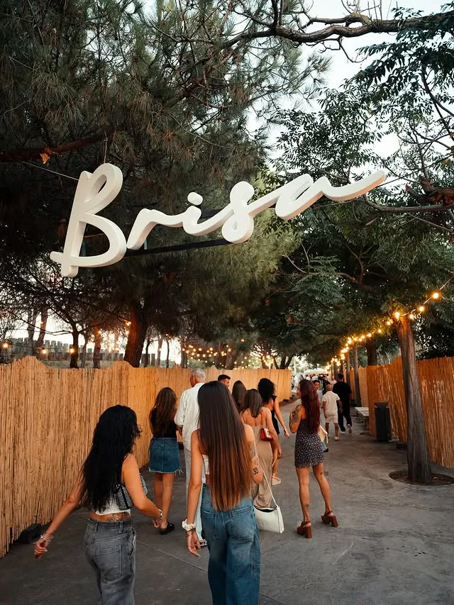 El rótulo Brisa colgado entre pinos en la entrada del recinto