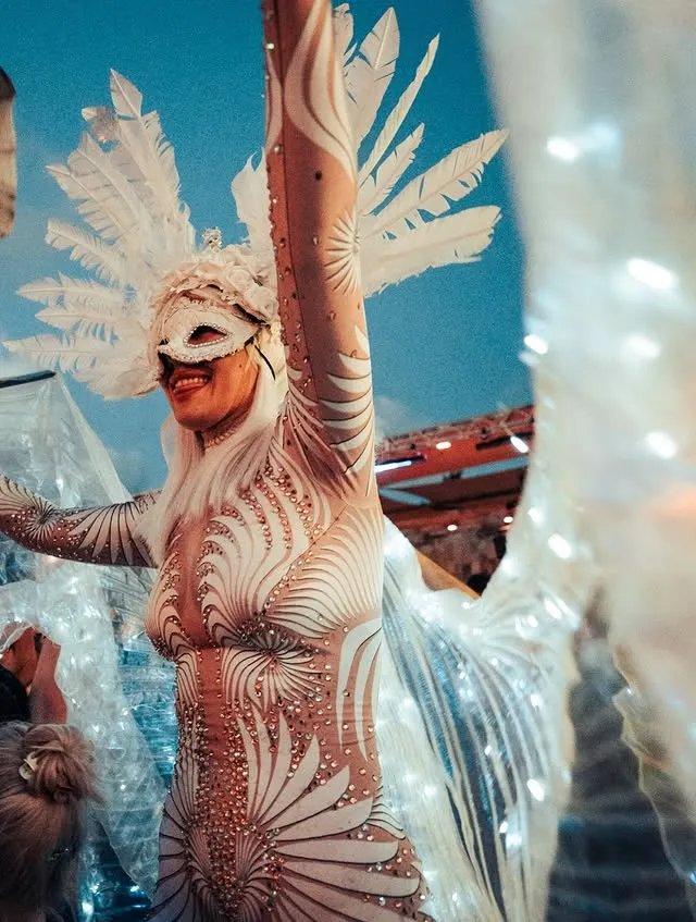 Artista con plumas blancas sobre el escenario al anochecer