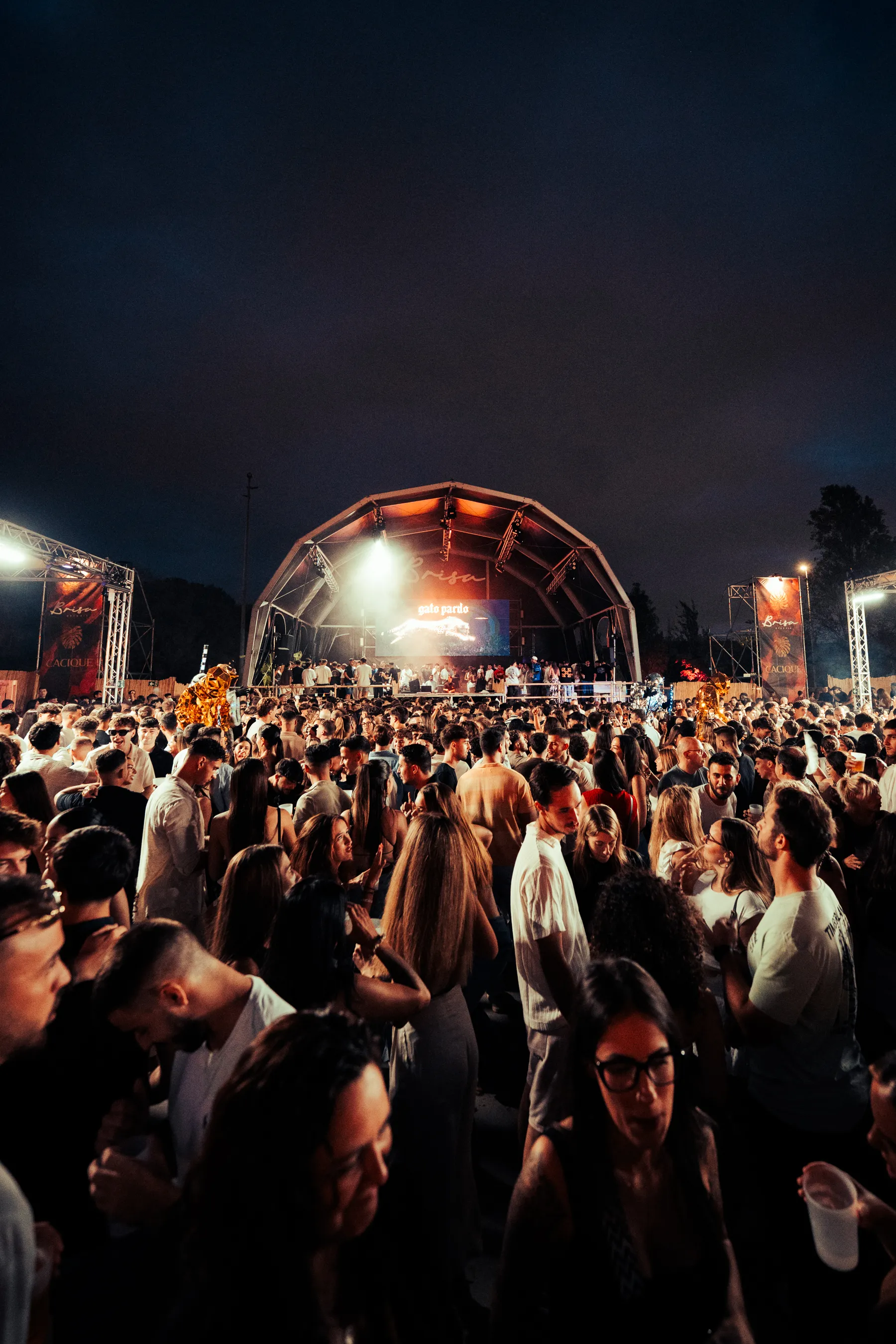 Público llenando el recinto de noche frente al escenario iluminado de Brisa Open Air
